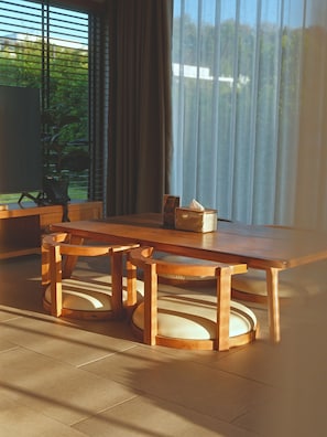 A wooden dining table with chairs, a small table with a tissue box, and a potted plant. - THE CAMPIAN (Chiang Dao)