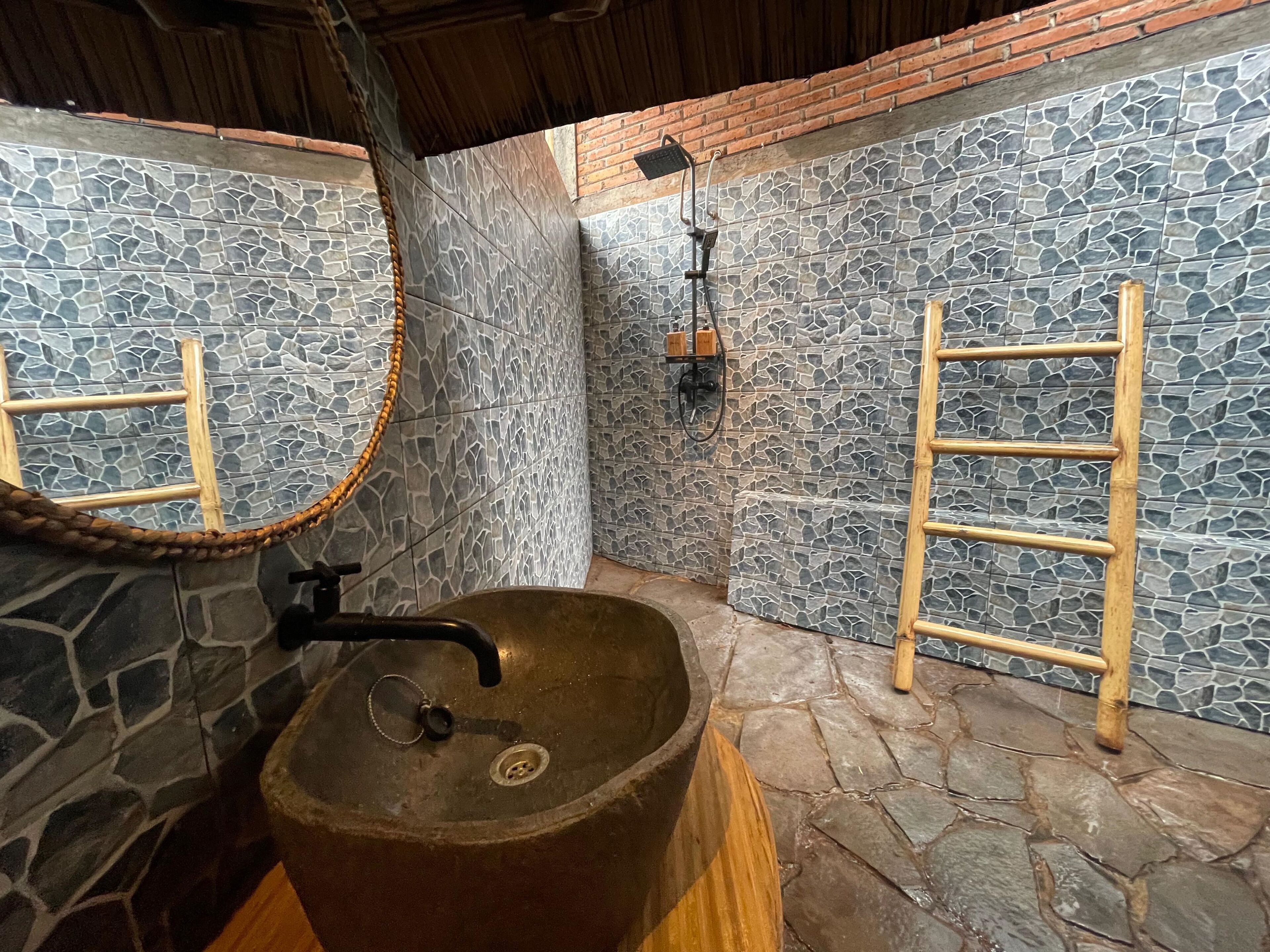 A bathroom with a stone sink, wooden ladder, and a mirror.