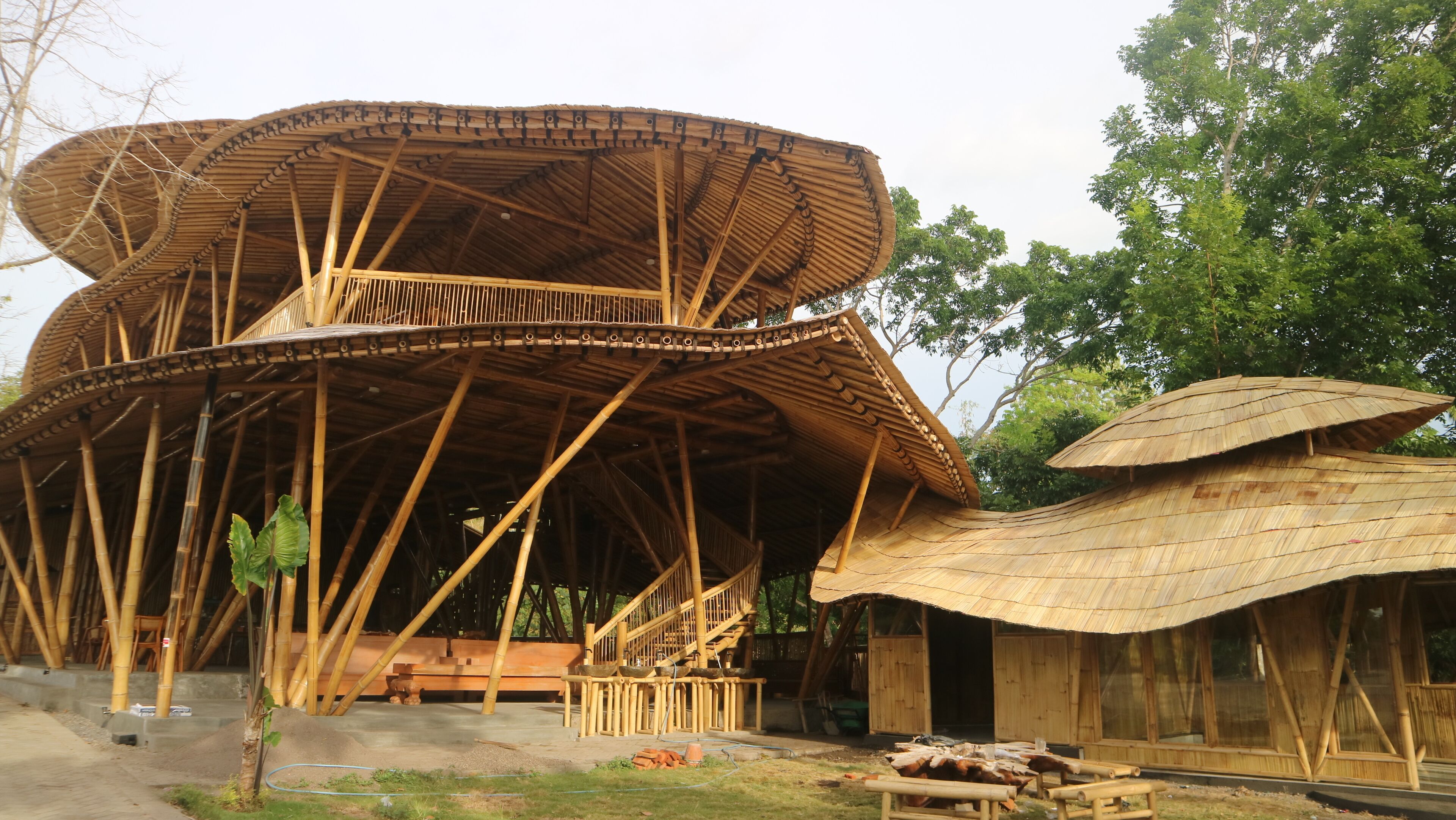 A bamboo structure with a curved roof and a wooden bench.