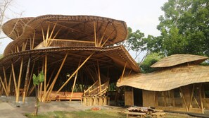 A bamboo structure with a curved roof and a wooden bench.