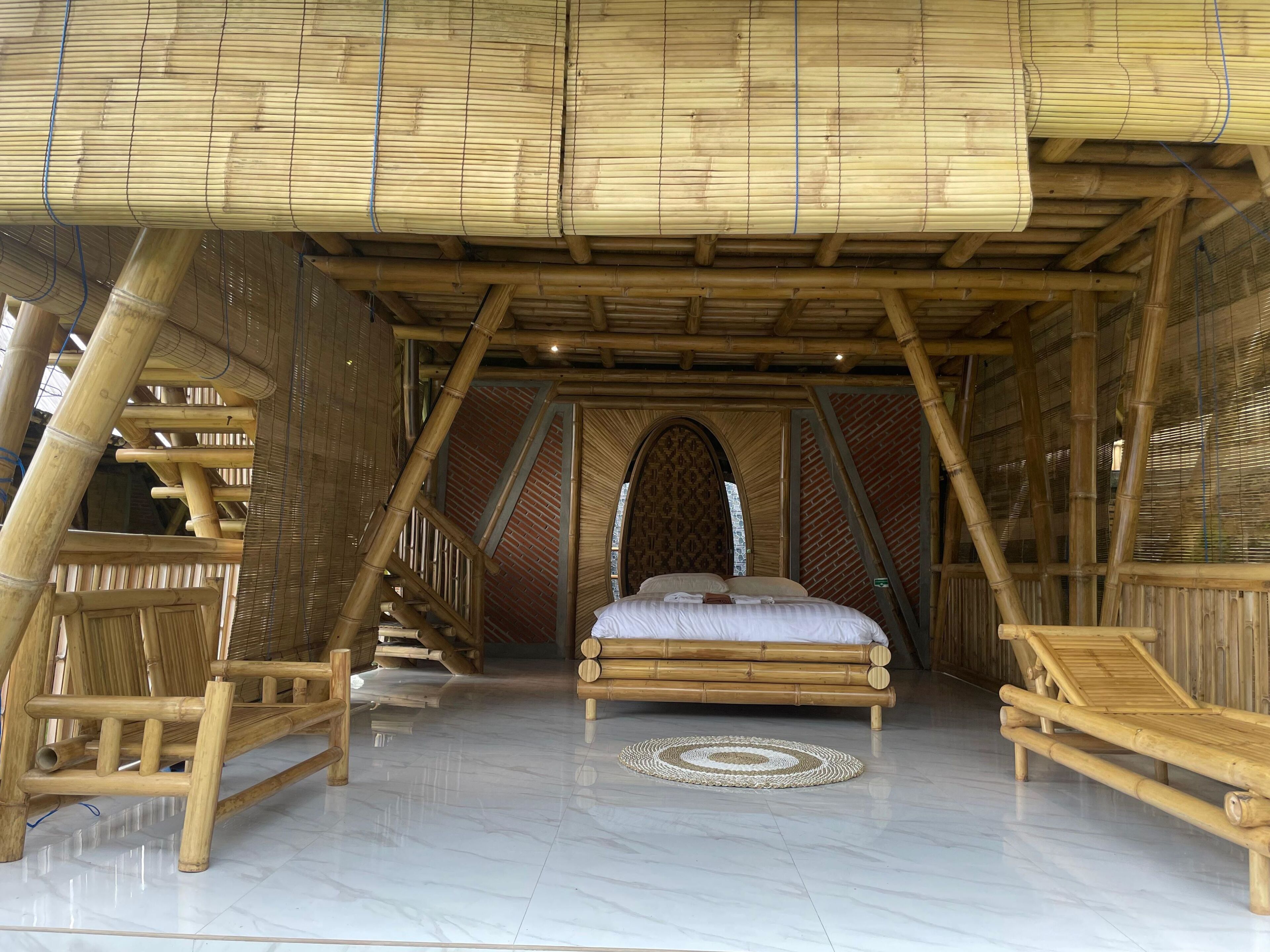 A room with a bed, a small table, and a chair, all made of bamboo.