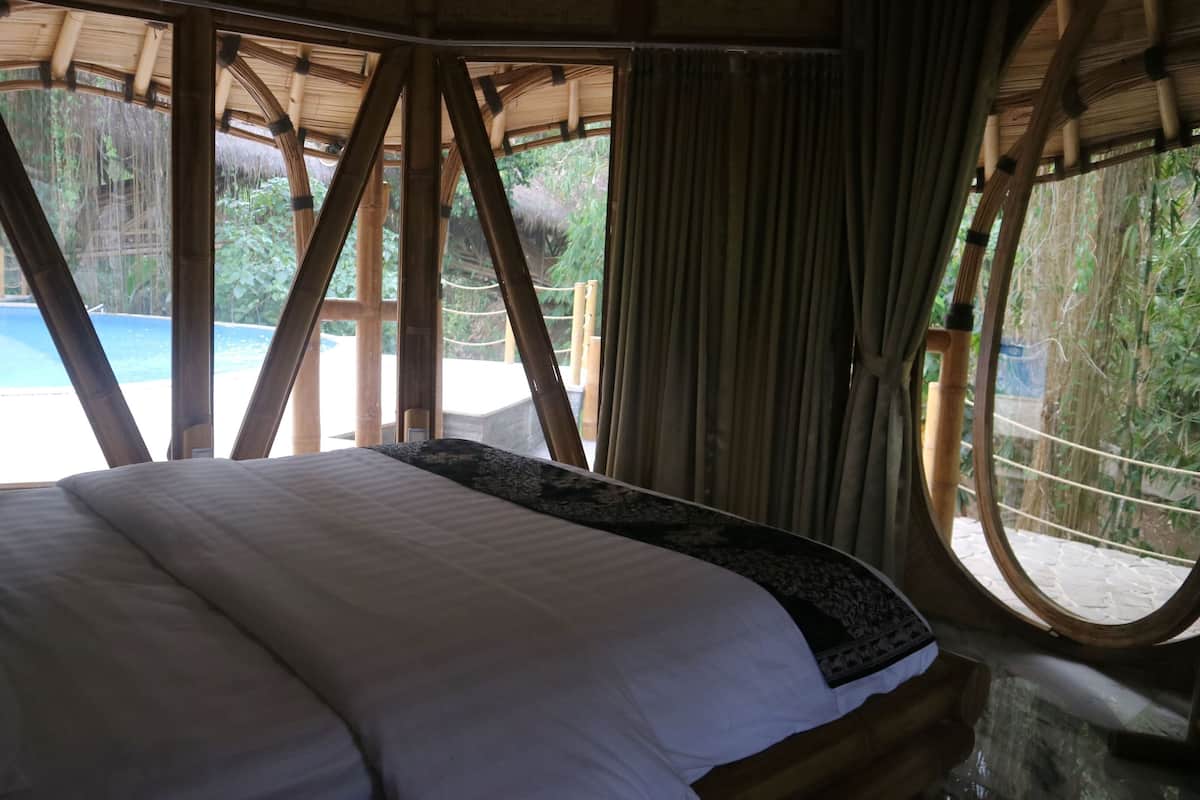 Ein Zimmer mit einem Bett, großen Fenstern und Blick auf einen Pool.