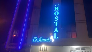 Un edificio con un letrero de neón que dice "HOSTAL El Rancho".