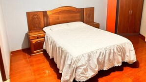 Un dormitorio con una cama de madera, una mesita de noche, un armario y un cuadro enmarcado en la pared.