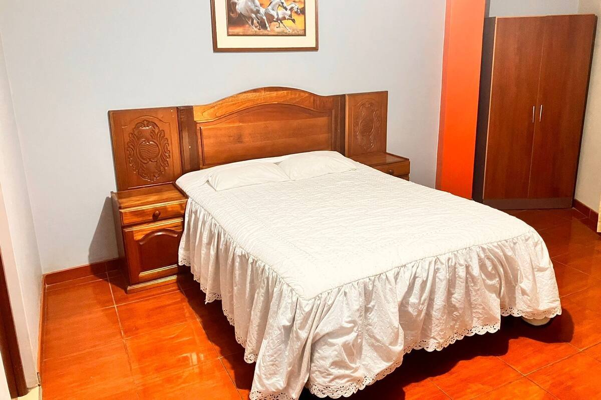 Une chambre à coucher avec un lit en bois, une table de chevet, une armoire et un tableau encadré au mur.