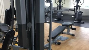 A gym with various exercise equipment, including a bench press, a squat rack, and a cable machine. - Amourette's Studio at Mesaavirre Garden (Bacolod)