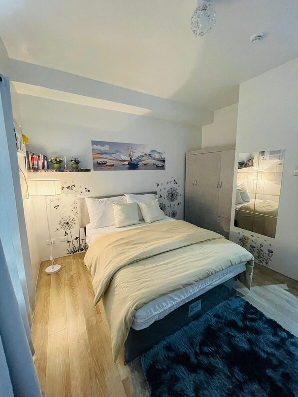 Une chambre à coucher avec un lit, une table de chevet, une lampe et un tableau au mur.