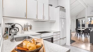 A modern kitchen with white cabinetry, a built-in oven, and a dining area with a table and chairs. - "Bjart" - 1.5km from the sea by Interhome (Væggerløse)