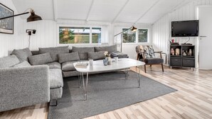 A modern living room with a grey sectional sofa, a white coffee table, and a TV mounted on the wall. - "Bjart" - 1.5km from the sea by Interhome (Væggerløse)