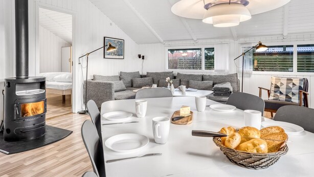 A modern living room with a fireplace, a dining area with a table set for two, and a cozy seating area with a sofa. - "Bjart" - 1.5km from the sea by Interhome (Væggerløse)