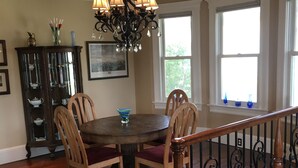 A dining area with a wooden table and chairs, a chandelier, and a staircase with a wrought iron railing. - Fully Renovated 1905 Victorian in Historic Napa Neighborhood  (Napa)