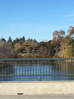 A concrete barrier with vertical bars, a body of water, and trees in the background. - Fully Renovated 1905 Victorian in Historic Napa Neighborhood  (Napa)