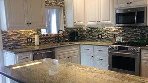 A kitchen with white cabinetry, a granite countertop, a stainless steel oven, and a microwave. - Fully Renovated 1905 Victorian in Historic Napa Neighborhood  (Napa)