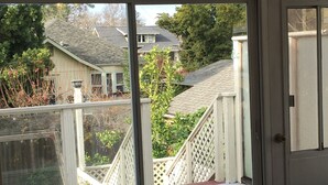 A room with a sliding glass door leading to a balcony with a view of neighboring houses and a wooden deck. - Fully Renovated 1905 Victorian in Historic Napa Neighborhood  (Napa)