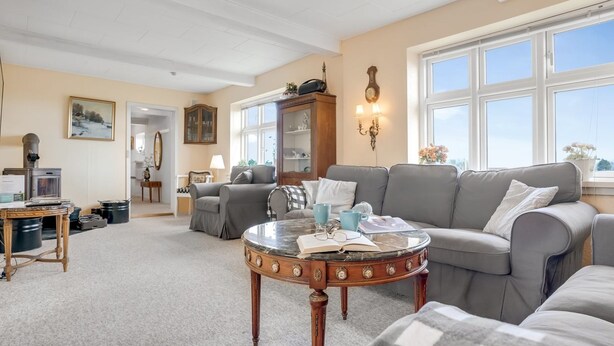 A cozy living room with a grey sofa, a round coffee table, and a bookshelf.