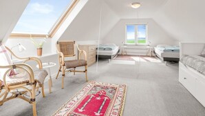 A spacious attic bedroom with a skylight, two beds, a large window, and a view of the sky.