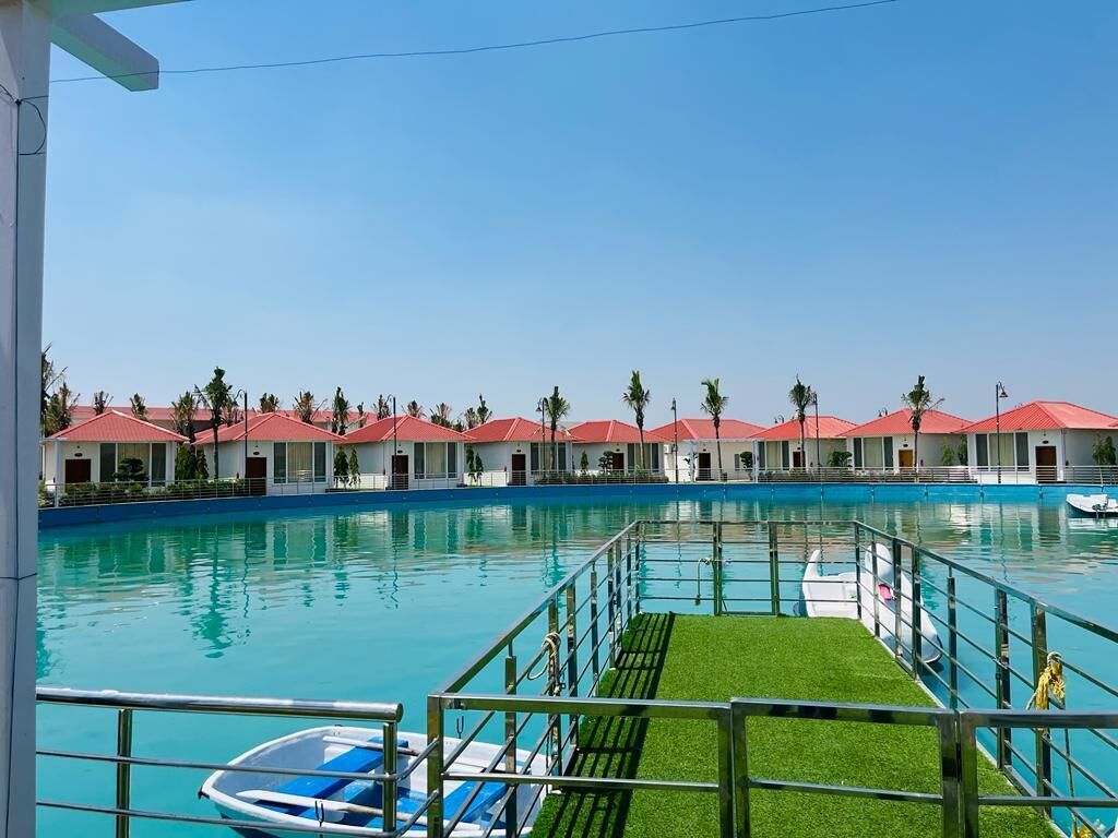 A swimming pool with a boat dock, surrounded by red-roofed buildings, and a clear blue sky.