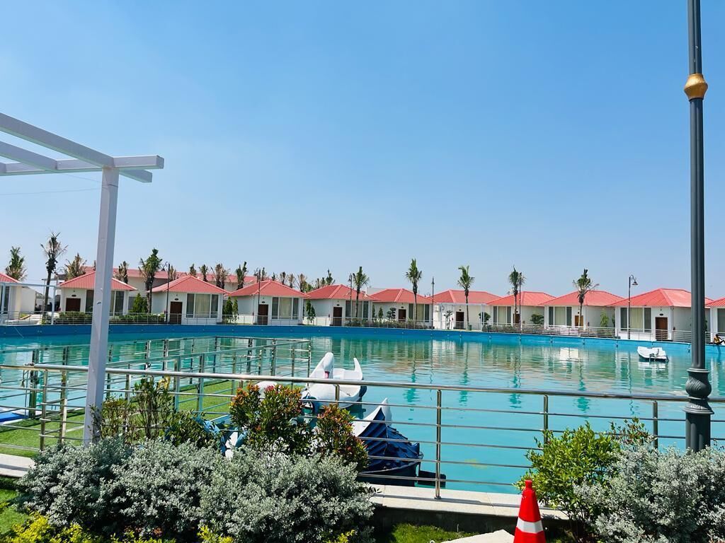 A swimming pool with a row of red-roofed buildings in the background.