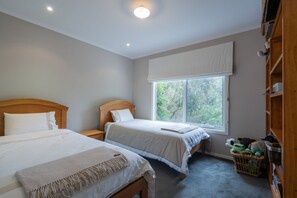 A bedroom with two beds, a large window, and a wooden wardrobe. - Casey (Anglesea)