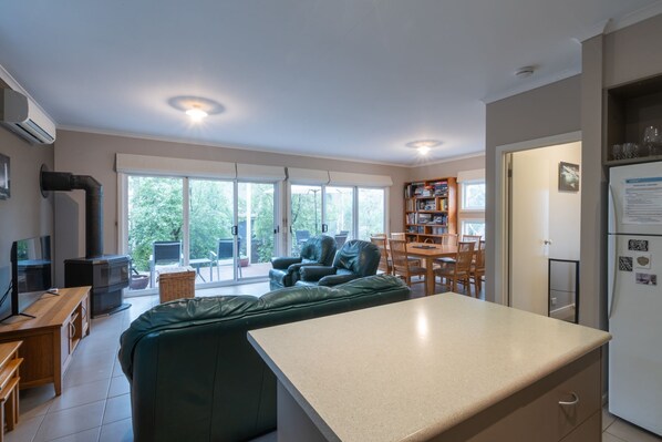 A modern kitchen with a dining area, a built-in sofa, and a large window.