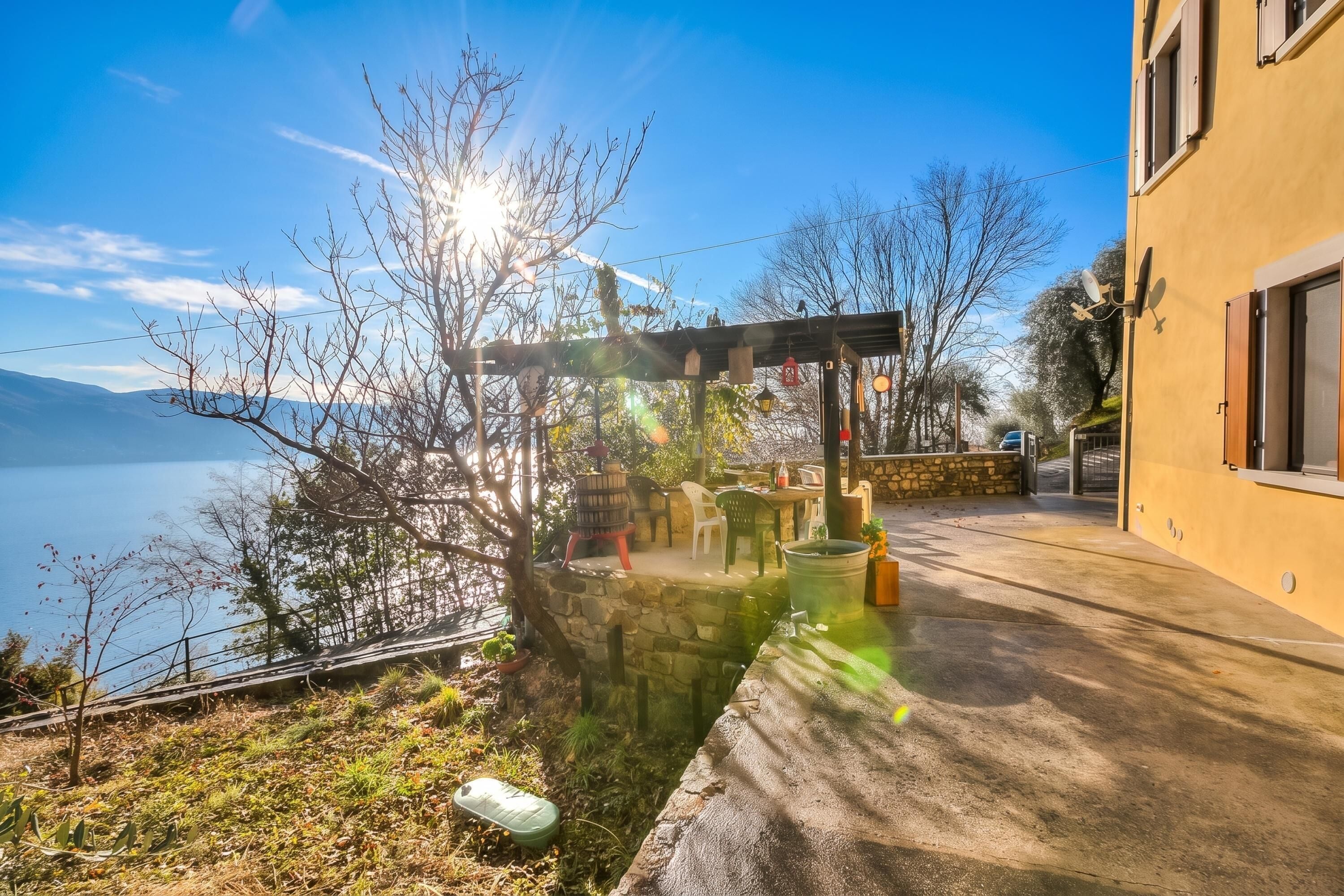 A patio with outdoor furniture, a stone wall, and a view of a body of water.