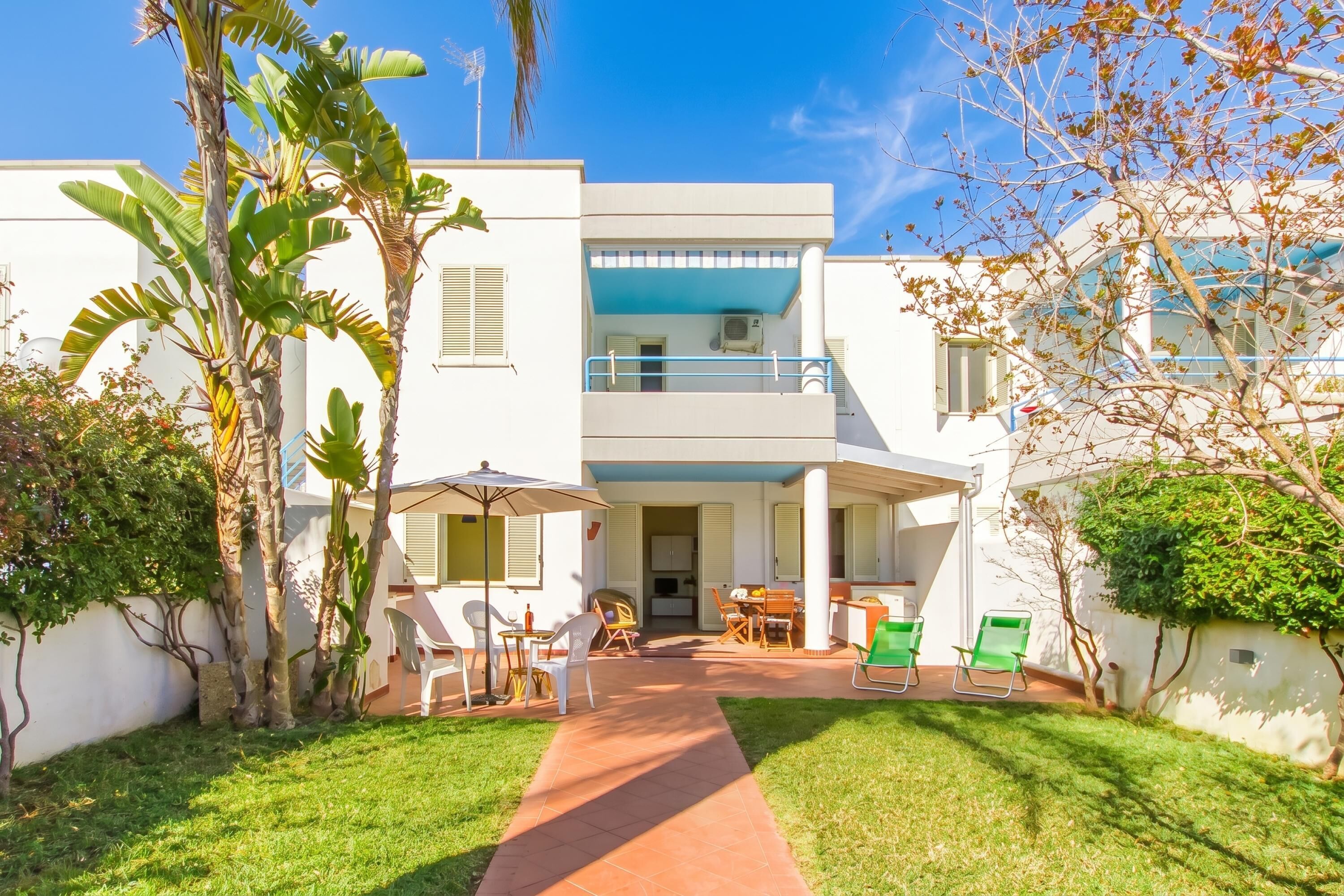 A modern two-story building with a covered patio, outdoor seating, and a well-maintained lawn.