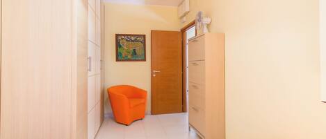 Habitación de hotel con una cama, una silla, un armario, una puerta y un cuadro en la pared.