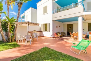 A two-story building with a patio area featuring outdoor furniture and a green lawn. - Villetta Relax with pool in residence (Melendugno)