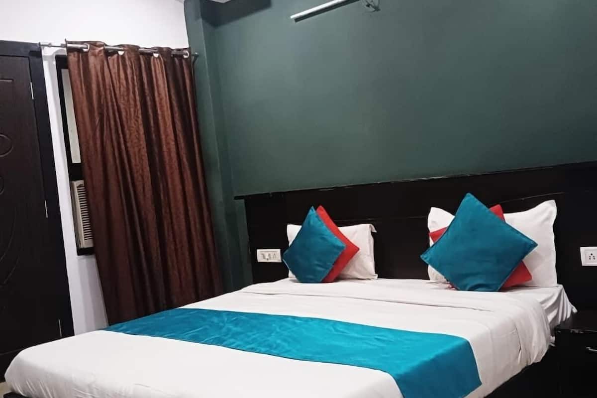 A neatly made bed with white and blue bedding, a black headboard, and a teal throw blanket.