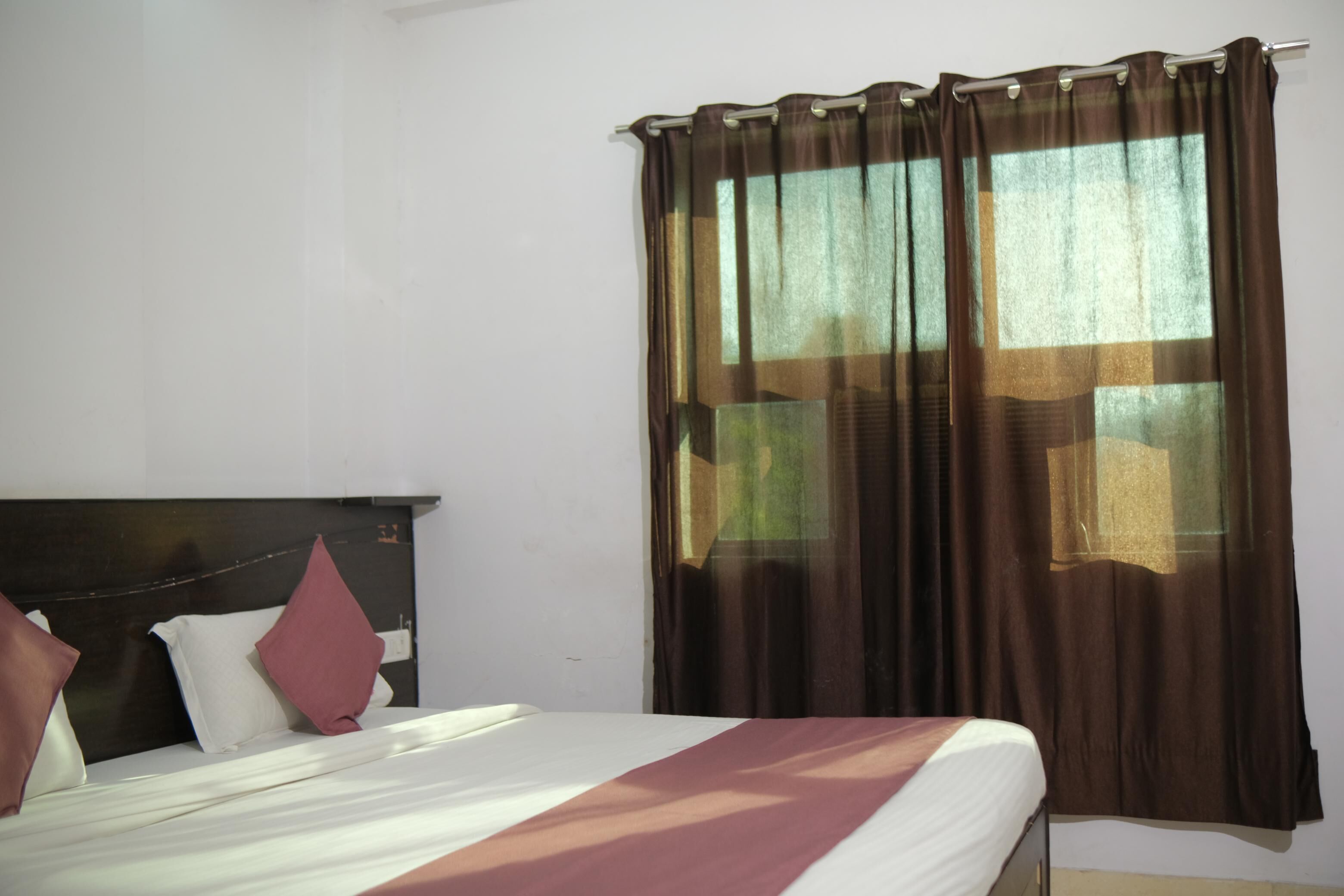 Ein Hotelzimmer mit Bett, Kopfteil und einem Vorhangfenster.
