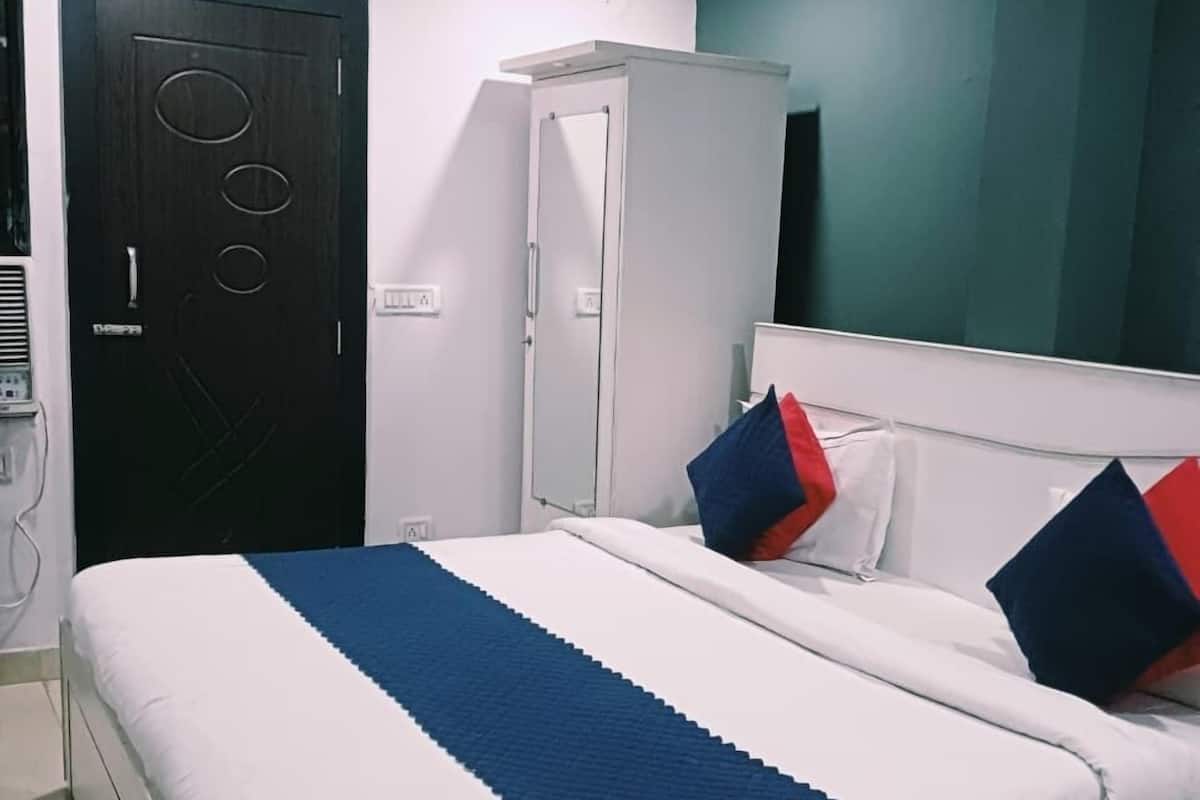 A neatly made bed with a white and blue striped bedspread, a white headboard, and two pillows with red and blue accents.