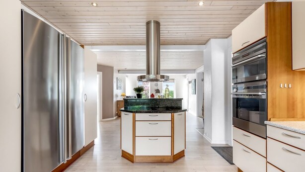Een moderne keuken met een centraal eiland, roestvrijstalen apparatuur en houten keukenkastjes.