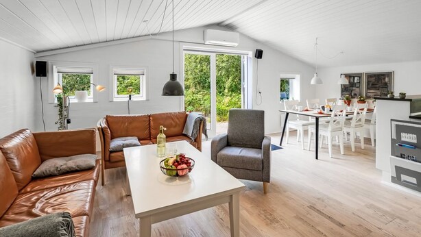 Ein geräumiger Wohnbereich mit hoher Decke, einem Esstisch, einer Couch und einer Küchenzeile.