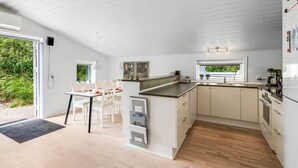 Eine moderne Küche mit weißen Schränken, einer zentralen Kochinsel und einem Essbereich mit Tisch und Stühlen.