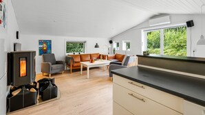 Ein modernes Wohnzimmer mit Kamin, einer Couch, einem Couchtisch und einer Küchenzeile mit Arbeitsfläche.