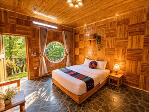 A wooden-paneled room with a bed, a round window, and a stone floor. - MT House Sa Pa (Sa Pa)