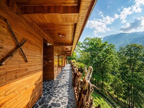 A wooden corridor with a stone floor leading to a balcony overlooking a forested valley. - MT House Sa Pa (Sa Pa)