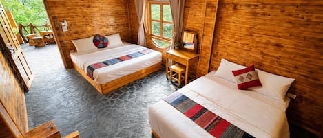A wooden cabin with two beds, a small desk, and a window with curtains.