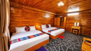 Una cabaña de madera con dos camas, una mesita y un armario.