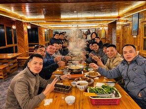 A group of people dining in a wooden interior with tables and benches. - MT House Sa Pa (Sa Pa)