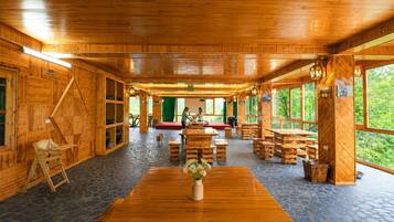 A wooden interior with a central table, benches, and a stage area.