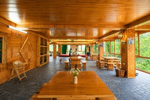 A wooden interior with a central table, benches, and a stage area. - MT House Sa Pa (Sa Pa)