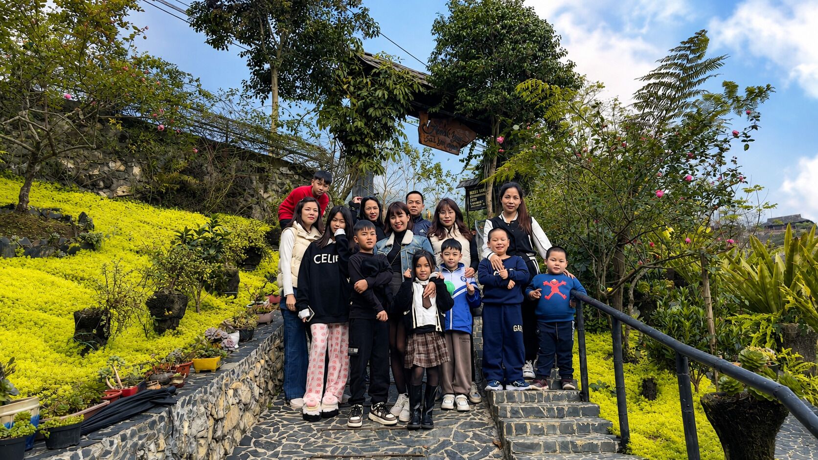 Un grupo de personas de pie sobre escalones de piedra, rodeado de vegetación y un muro de piedra.