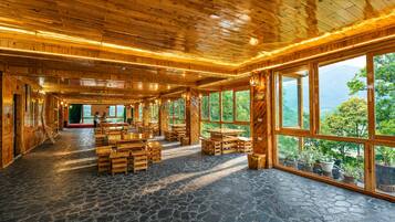 Un intérieur spacieux, avec des éléments en bois, un sol en pierre et de grandes fenêtres offrant une vue sur l’extérieur.