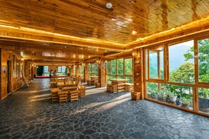A spacious wooden interior with stone flooring and large windows offering a view of the outdoors. - MT House Sa Pa (Sa Pa)