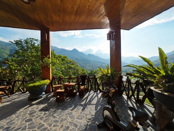 Relax in a serene outdoor space with a stationary bike and comfortable seating amidst breathtaking mountain views.
