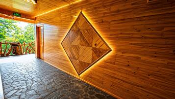 Interior de madera con suelo de piedra, un panel de pared geométrico y señal de salida visible.