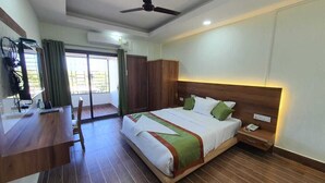 Una camera d'albergo con un letto, una testiera in legno, un comodino e una scrivania con una sedia.