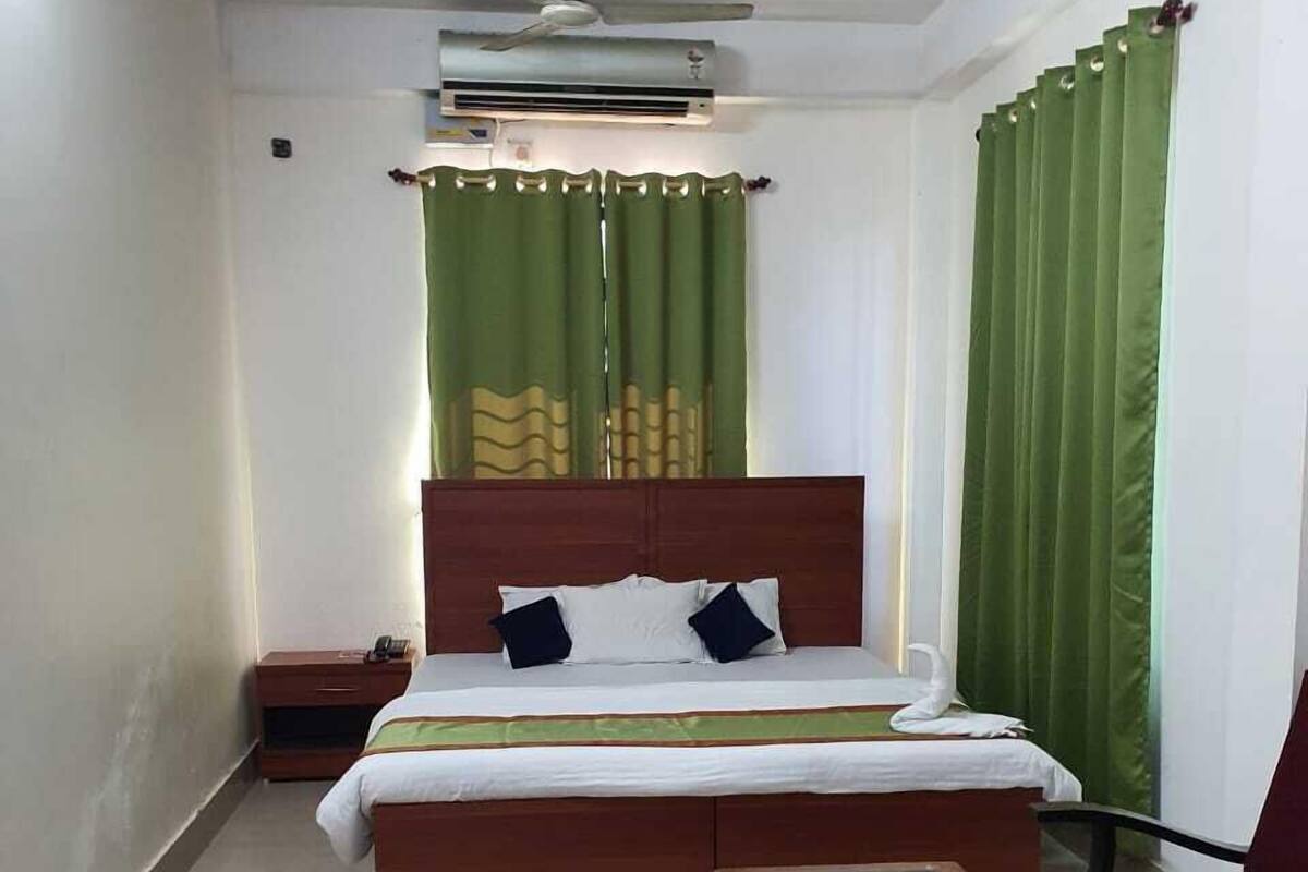 A hotel room with a bed, a nightstand, a table, a chair, and a ceiling fan.