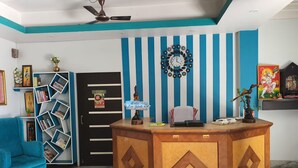 Una zona reception di un hotel con una scrivania in legno, una sveglia appesa al muro e una parete a righe blu.